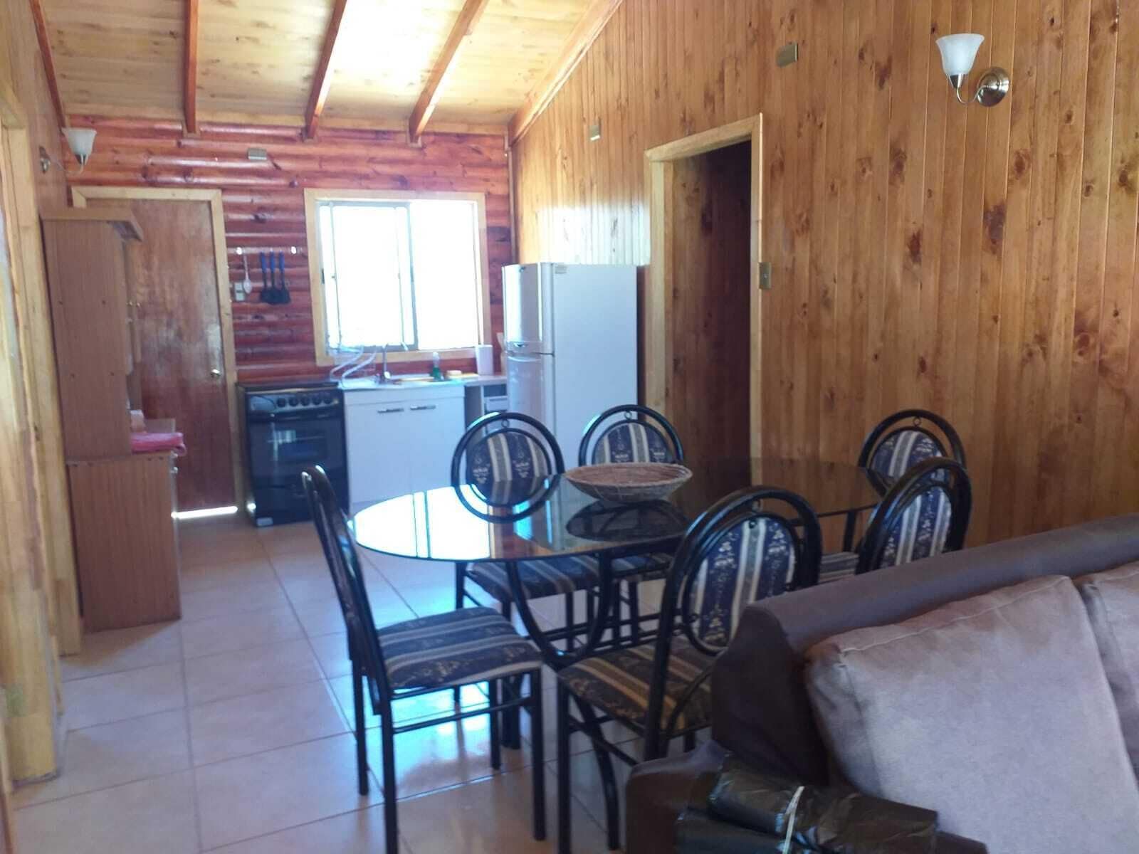 L’intérieur d’un chalet en bois comprend un coin repas, une cuisine et un canapé.