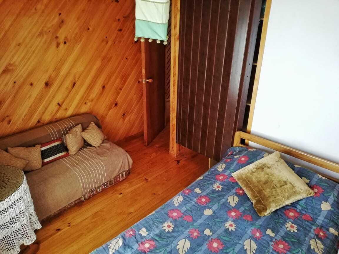 A wooden room with a bed, a sofa, and a small table.