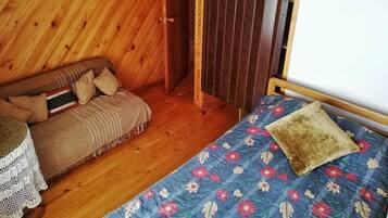 A wooden room with a bed, a sofa, and a small table.