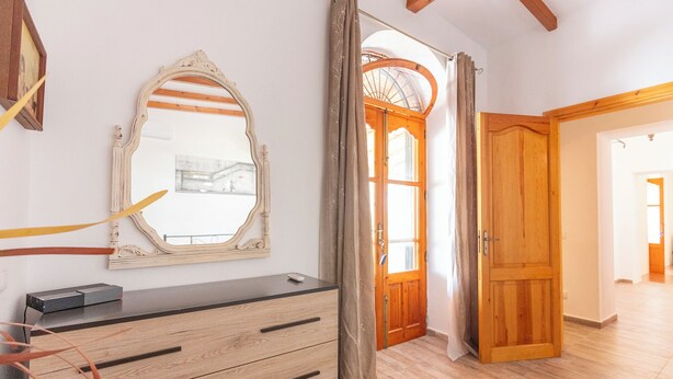 Una habitación con un aparador de madera, un espejo y una puerta de madera que da a otra estancia.