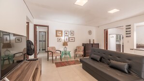 Ein modernes Wohnzimmer mit einer Couch, Sesseln, einem Couchtisch und einem Fernseher.