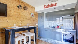 A compact kitchen with wooden walls, a dining area with stools, and a tiled backsplash.