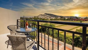 A balcony with wicker chairs and a table, overlooking a scenic landscape with a sunset. - Ionian Serenity House (Zakynthos)