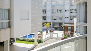 A modern building with multiple balconies, a pool area, and outdoor seating. - Apto em prédio c/ piscina 350m da praia RTG208 (Florianópolis)