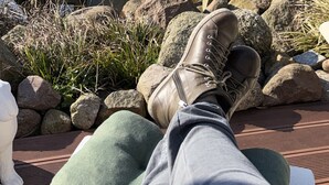 A person relaxing by a pond with rocks and plants, a bench, and a building in the background. - Apartment 'Kleine Oase Stuhr im Container E G' with Shared Terrace, Garden & Wi-Fi (Stuhr-Brinkum)