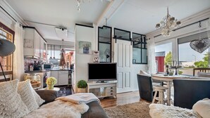 A modern living room with a sofa, a TV, and a dining area with a table and chairs. - Apartment 'Kleine Oase Stuhr im Container E G' with Shared Terrace, Garden & Wi-Fi (Stuhr-Brinkum)