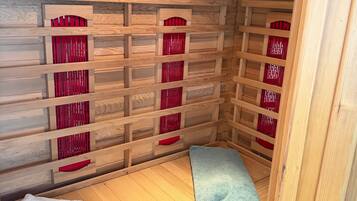 Ein Zimmer aus Holz mit einem Bett, einer Bank und einer Wand mit roten Lamellen.