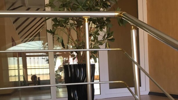 A modern staircase with a glass railing, a potted plant, and a view of the interior space. - 3 storey Villa (Baku)