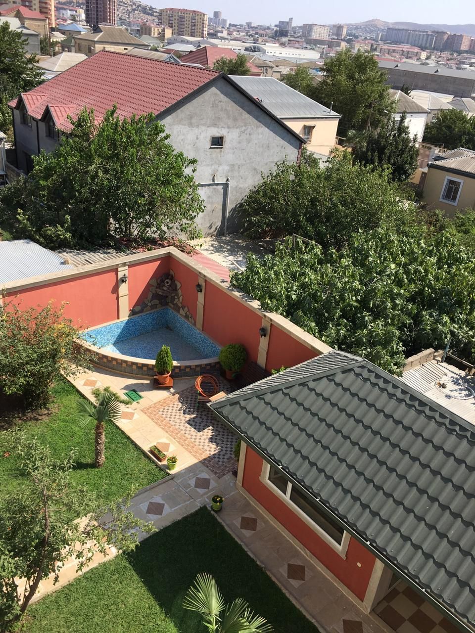Un quartier résidentiel doté d’une piscine, d’un bâtiment rouge et d’une terrasse carrelée.