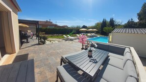 Ein Garten mit Schwimmbad, Gartenmöbeln und einer Terrassenfläche.