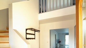Ein großzügiger Innenraum mit einer Treppe zu einer zweiten Etage, einem Flur und einer Tür.
