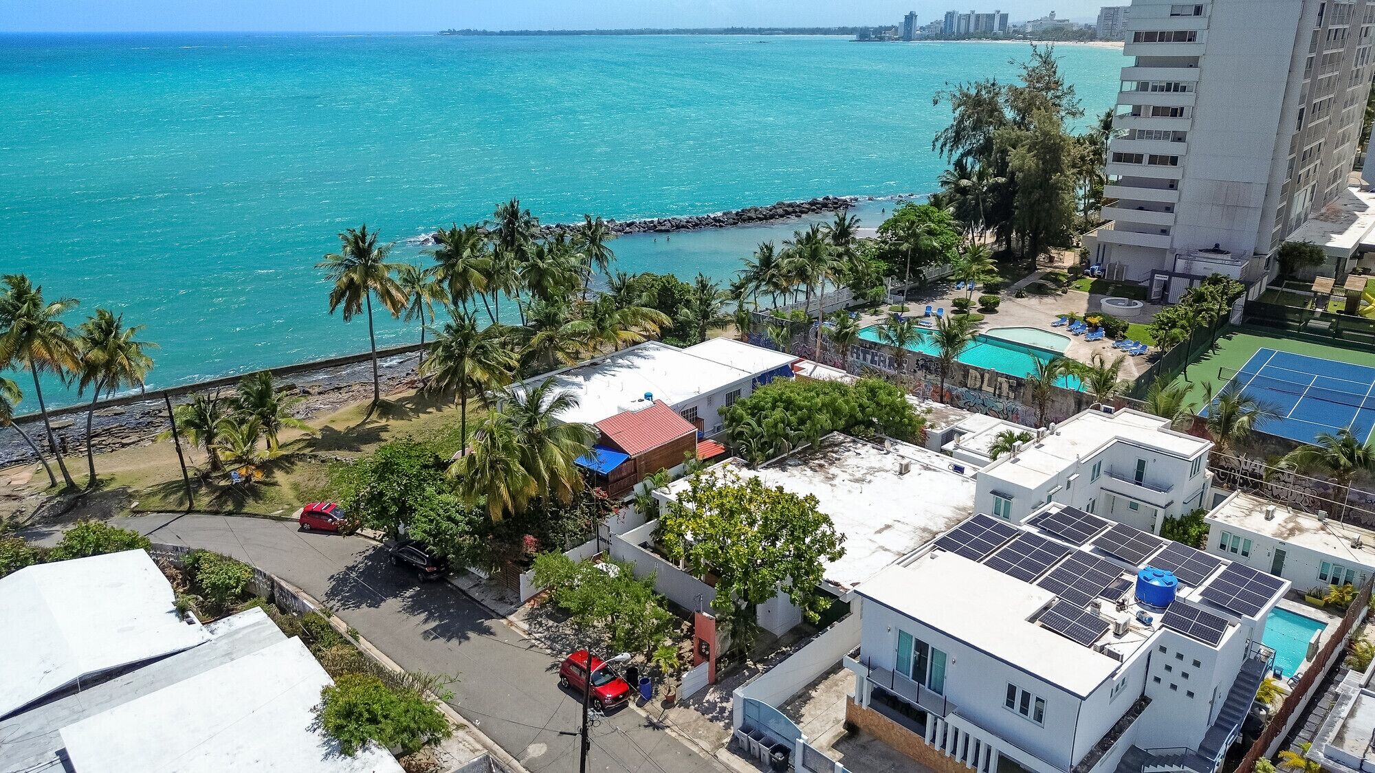 Zona residencial costera con vistas al mar, piscina y paneles solares en los tejados.