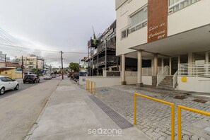 Vista de la calle con una clínica veterinaria, un edificio con un cartel que dice 'Solar da Cachoeira 2108', y una acera pavimentada con barandillas amarillas.