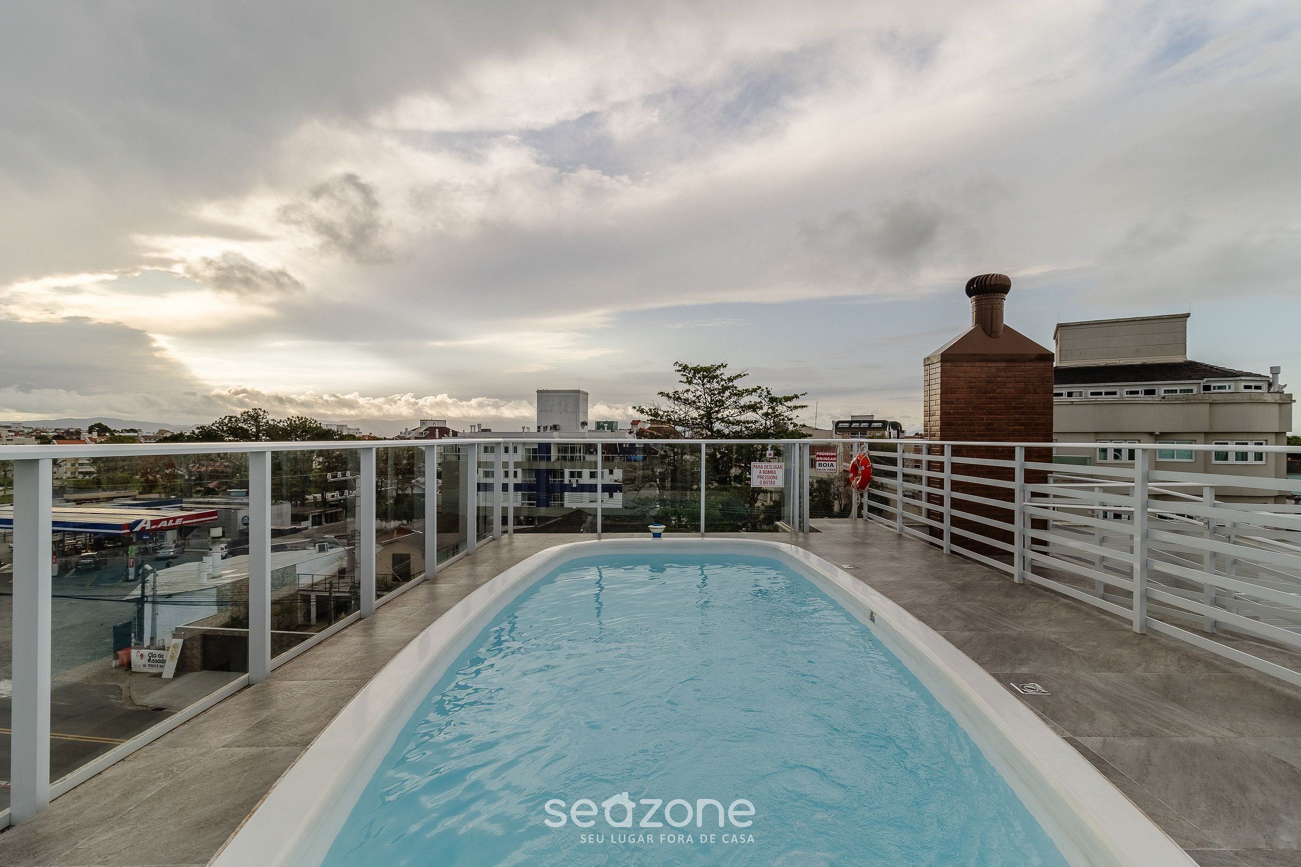 An indoor swimming pool with a view of the cityscape and a cloudy sky.