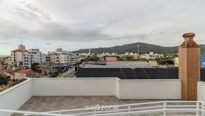 Un hôtel doté d’un toit plat, d’une cheminée en briques et offrant une vue sur un paysage urbain, avec des bâtiments et des collines en arrière-plan.