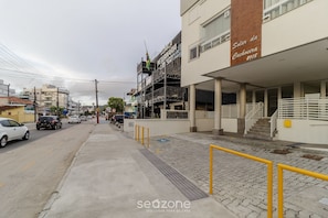 A street view with a veterinary clinic, a building with a sign reading "Solar da Cachoeira 2108", and a paved sidewalk with yellow railings.