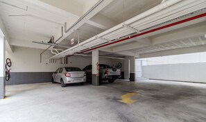A parking garage with two cars parked, a red pipe on the ceiling, and a yellow arrow on the floor. - Apt With Barbecue 280m From the Beach Rsc0102 (Florianópolis)