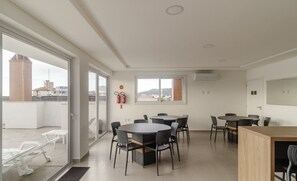 A modern hotel room with a large sliding glass door leading to a balcony, a round dining table with chairs, and a small kitchenette area. - Apt With Barbecue 280m From the Beach Rsc0102 (Florianópolis)