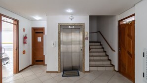 Ein Innenraum mit Aufzug, Treppe und einer Tür mit Feuerlöscher.