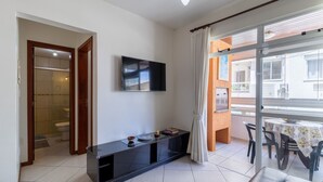 Ein modernes Wohnzimmer mit einer schwarzen Unterhaltungsanlage, einem Flachbildfernseher und einem Balkon mit Tisch und Stühlen.