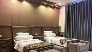 Ein Hotelzimmer mit zwei Betten, einer kleinen Couch und einem Nachttisch.