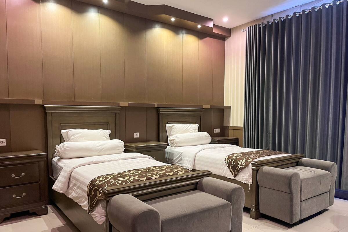 A hotel room with two beds, a small sofa, and a nightstand.