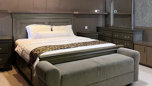 Ein modernes Schlafzimmer mit einem großen Bett, einer Bank, einem Schminktisch und einem Spiegel.