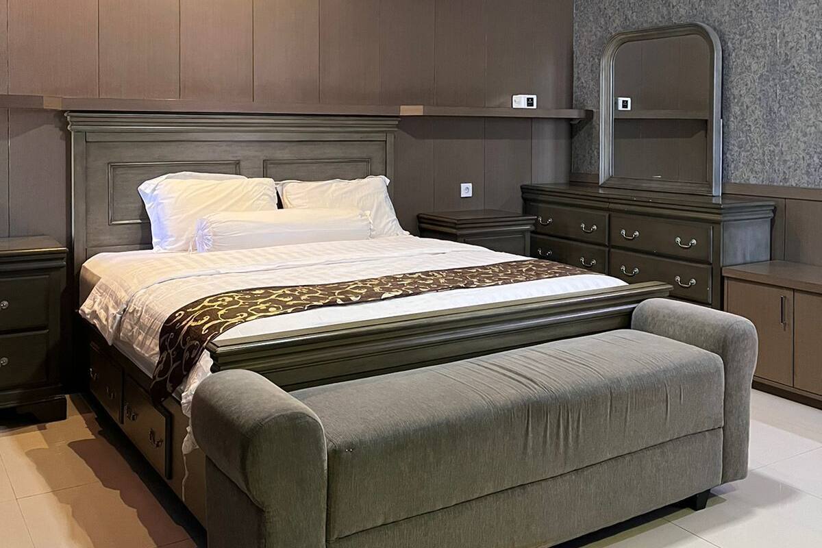 A modern bedroom with a large bed, a bench, a dresser, and a mirror.