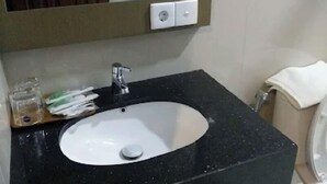 Ein Badezimmer mit einem schwarzen Granittischwaschbecken, einem Spiegel und einer Toilette.