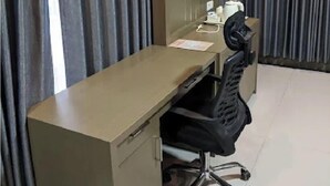 Ein Hotelzimmer mit Schreibtisch, Stuhl und einem an der Wand befestigten Flachbildfernseher.