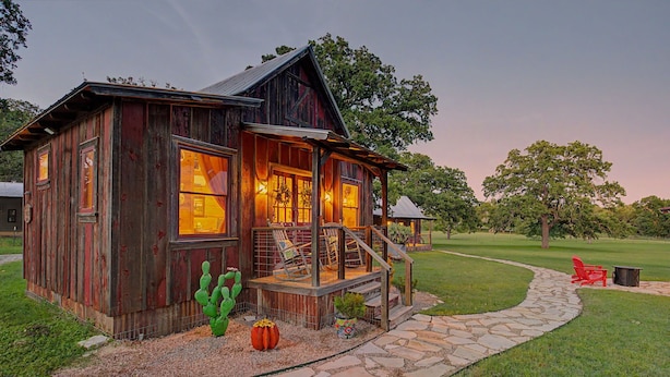 A rustic wooden cabin with a porch, stone pathway, and outdoor seating. - The Nest-A Cozy Rustic Escape for Two (Fredericksburg)