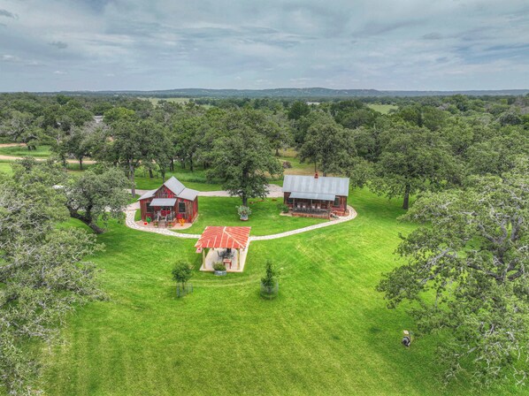 A rural landscape with two rustic cabins surrounded by lush greenery.