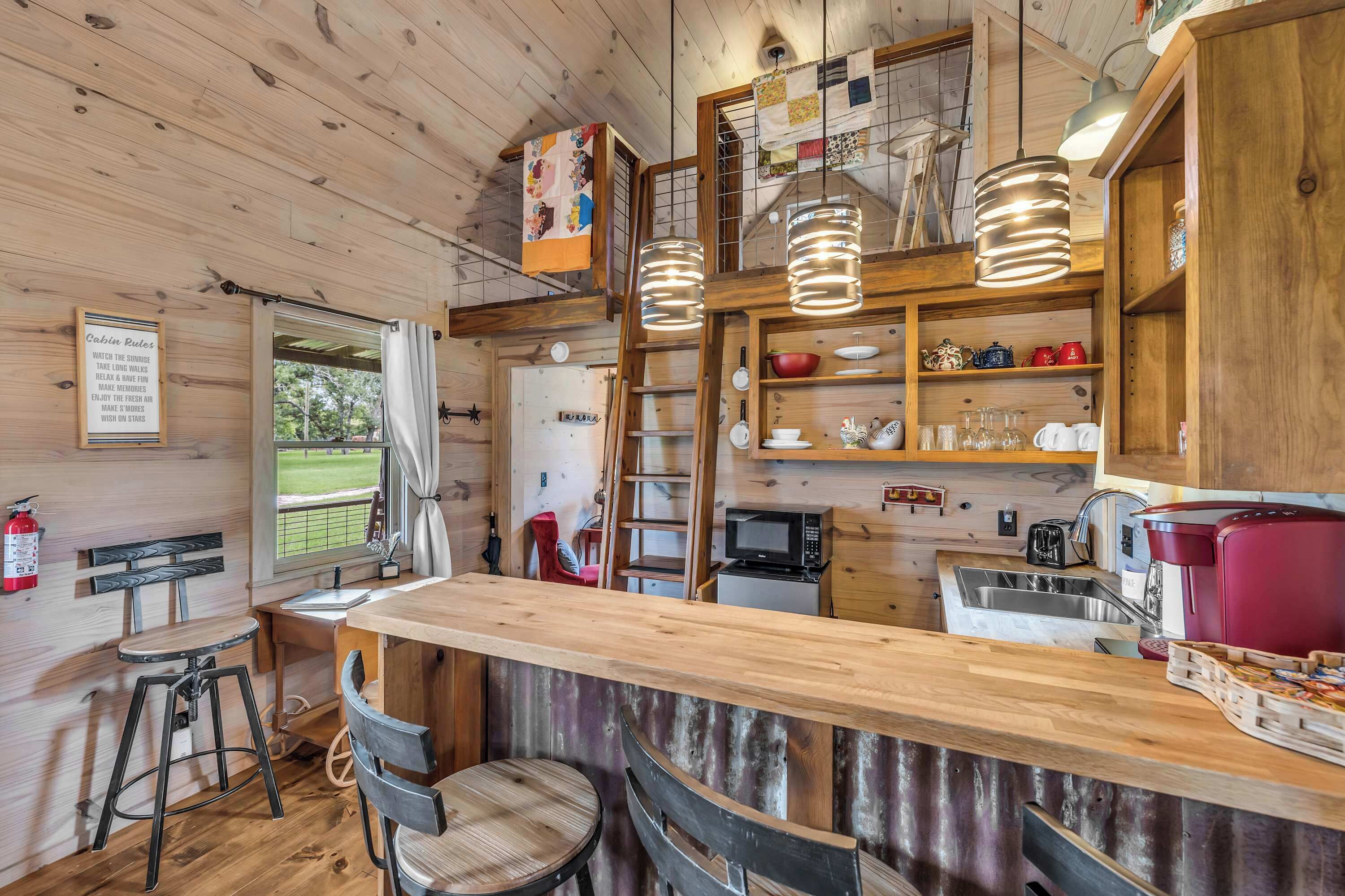 Interior de una cabaña de madera con cocina, barra y asientos.