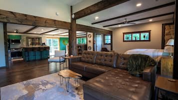 A spacious living area with a large leather sofa, a wooden coffee table, and a view of the kitchen and dining area.