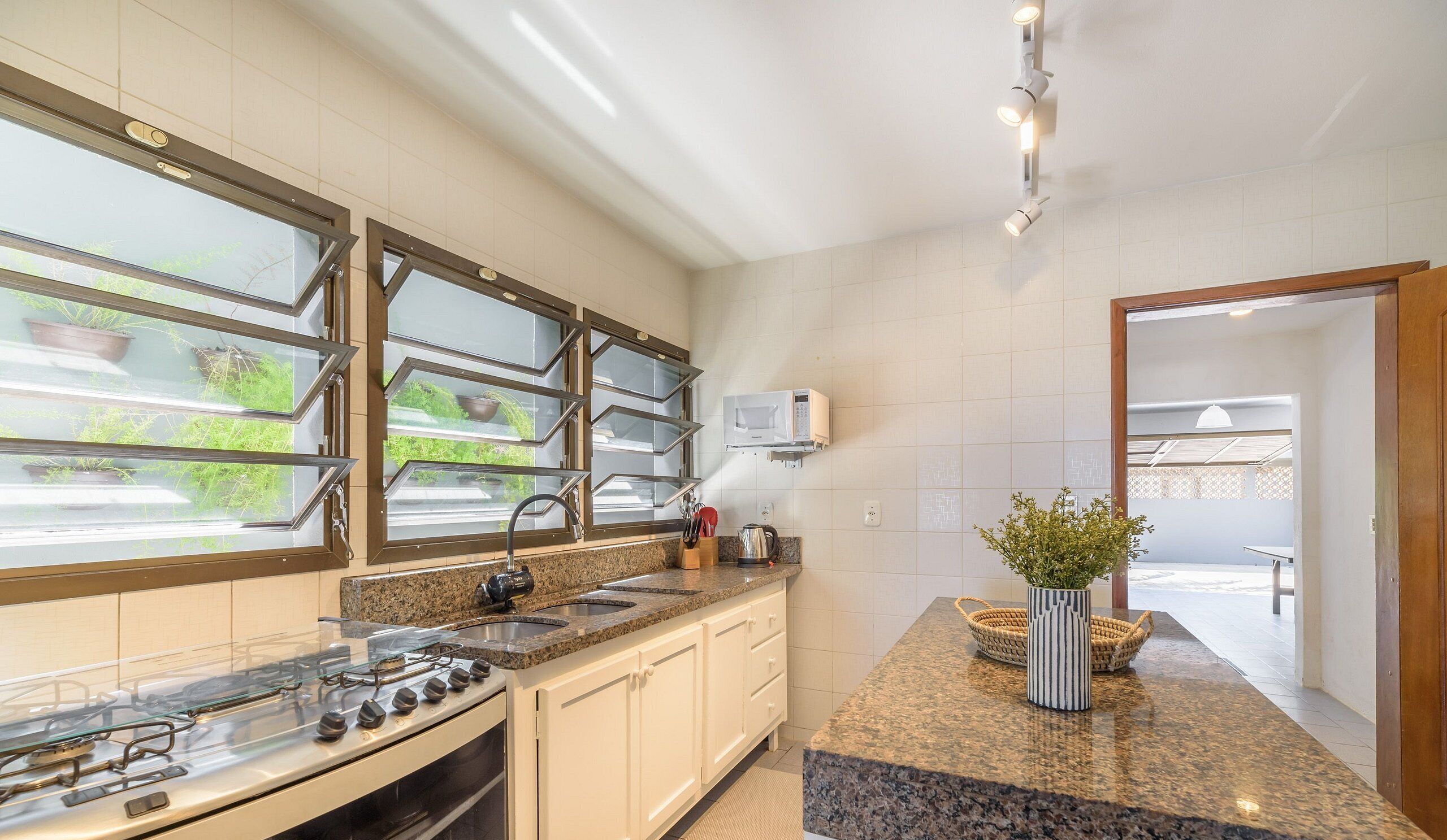A kitchen with a gas stove, a microwave, and a window with potted plants.