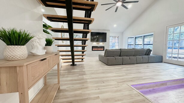 Ein modernes Wohnzimmer mit einer Holztreppe, einem grauen Sofa und einem Kamin.