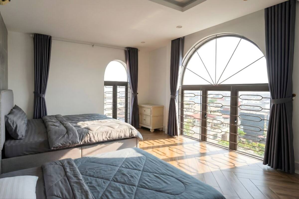 Un dormitorio moderno con dos camas, un ventanal grande y vistas a la ciudad.