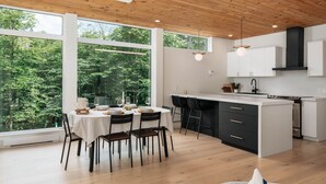 Una cocina moderna con una isla grande, armarios blancos y vistas a exuberante vegetación.