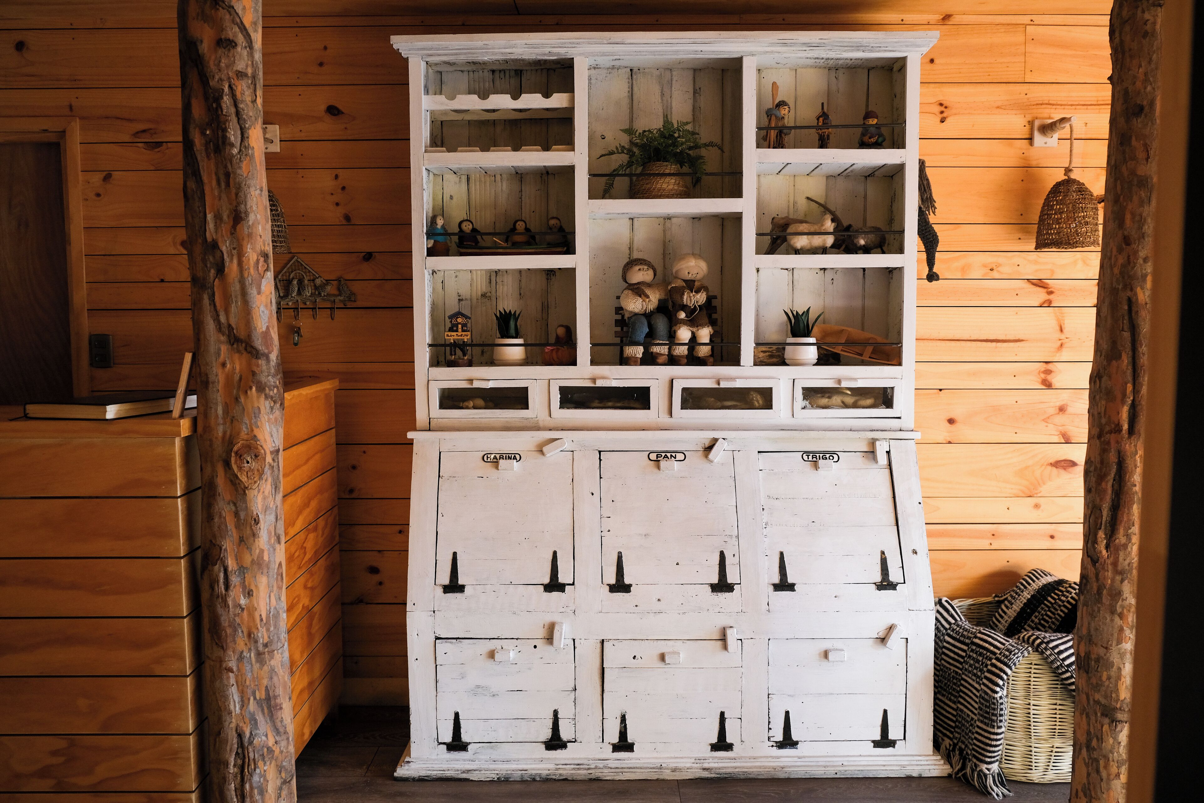 A wooden cabinet with multiple compartments, some containing figurines and plants.