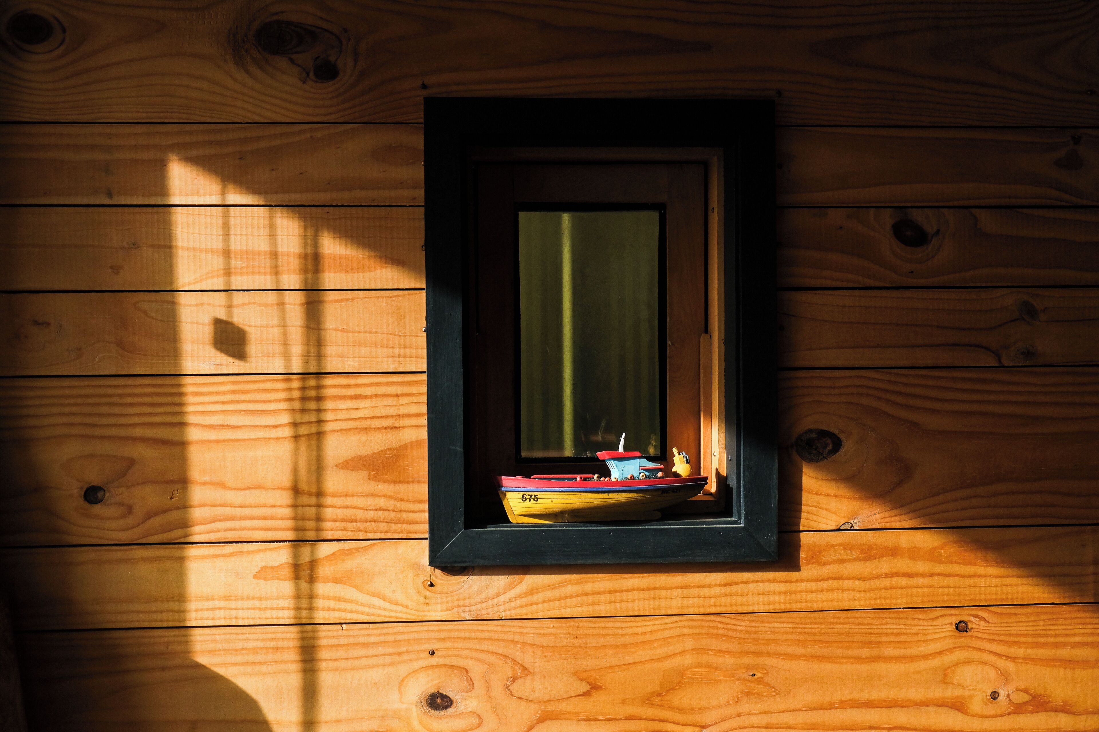 Una baita di legno con una finestra che mostra una barchetta in miniatura all'interno.