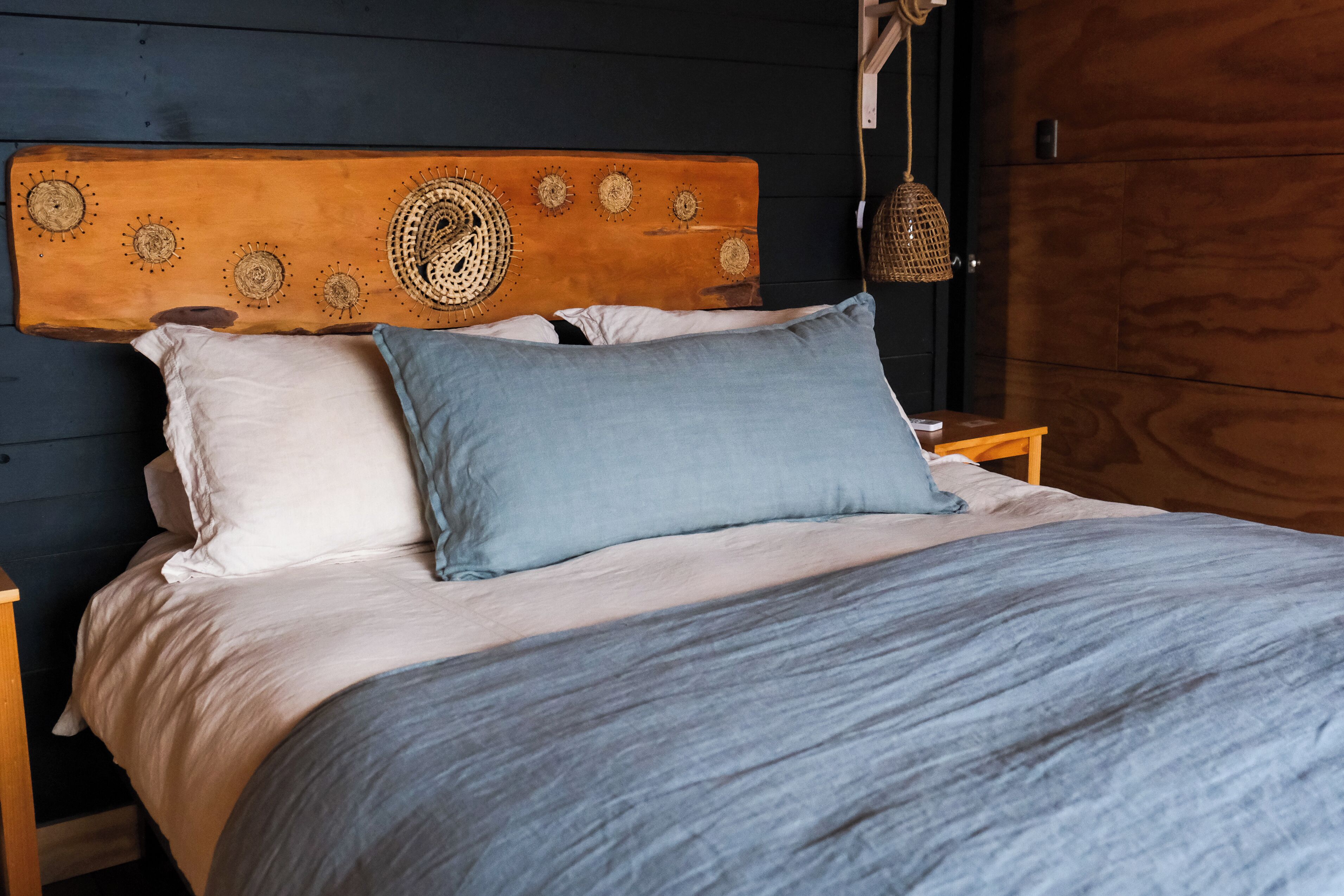 A bed with a wooden headboard, two pillows, and a blue blanket.