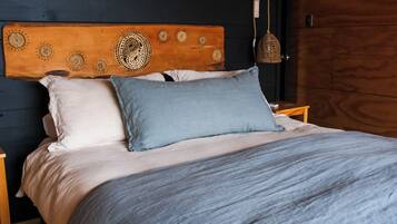 A bed with a wooden headboard, two pillows, and a blue blanket.