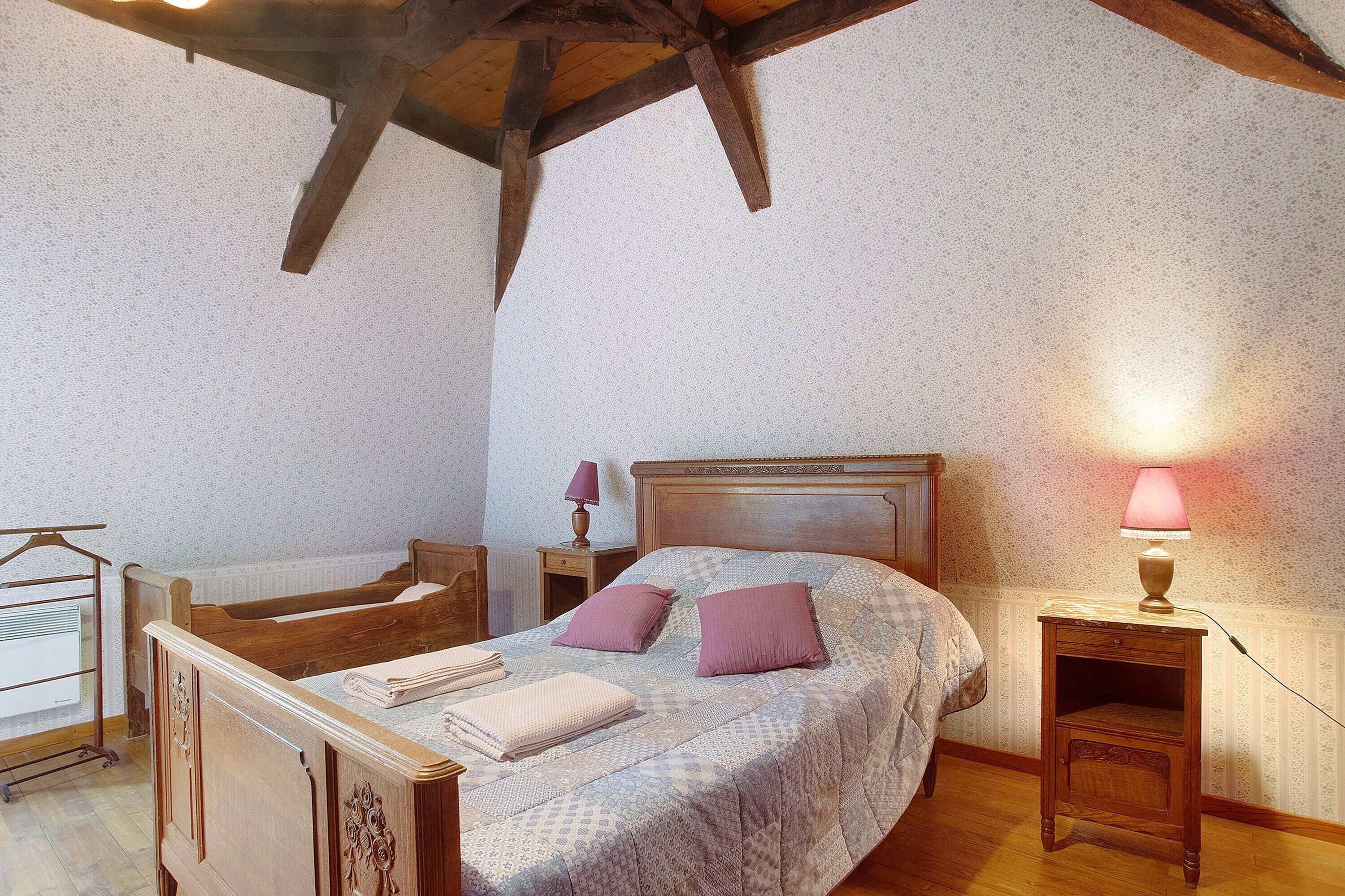 Een slaapkamer met een houten bed, een nachtkastje, een lamp en een stoel.