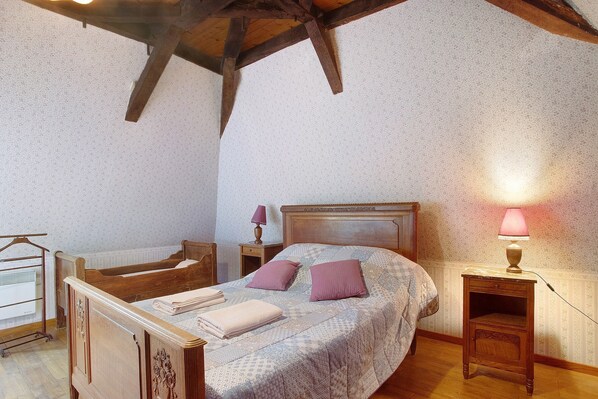 A bedroom with a wooden bed, a nightstand, a lamp, and a chair.
