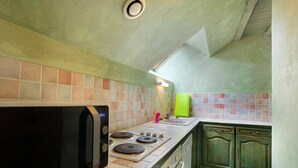 Une cuisine équipée d’un four à micro-ondes, d’une cuisinière et de meubles de couleur verte.