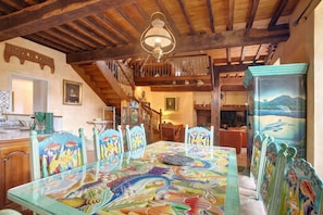 A dining area with a glass table, wooden chairs, and a staircase leading to an upper level. - Holiday Home Oustau Cassou (Sévignacq)
