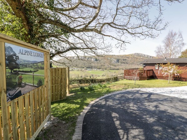 A wooden signboard for Alpine Lodges with a view of a rural landscape.
