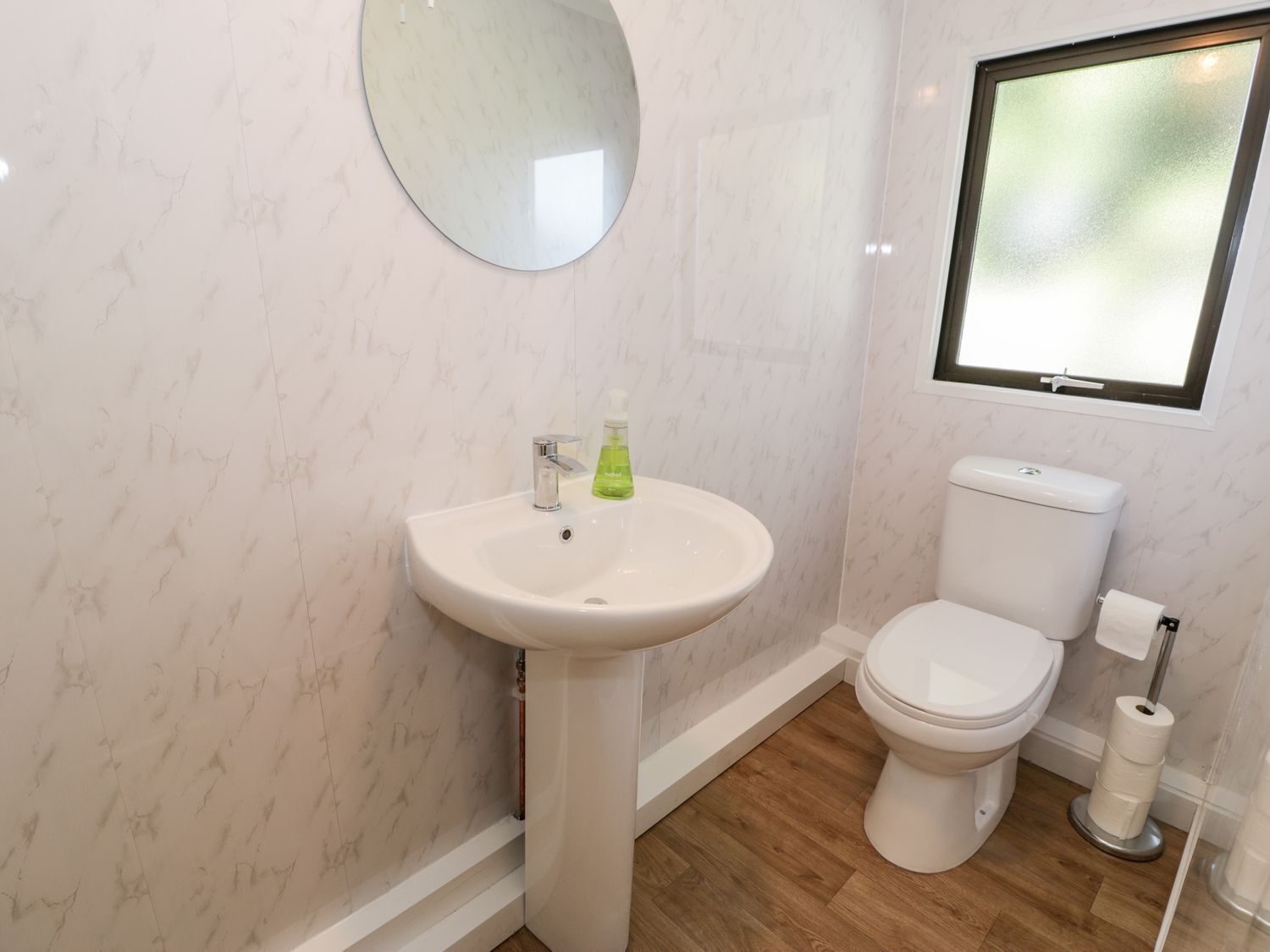 A bathroom with a white sink, a toilet, and a window with frosted glass.