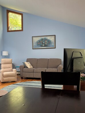 Un salon avec un canapé, un fauteuil et un tableau accroché au mur.