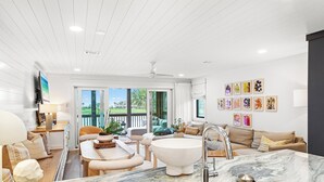 A modern living room with a marble countertop, a white bathtub, and a large window with a view of a green landscape. - Boardwalk Villas 298 - Community Pool, Lake Front, Great Amenities + Dining! (Miramar Beach)